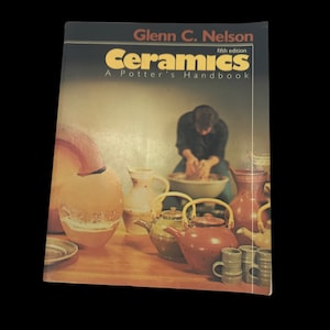 May include: A book titled "Ceramics: A Potter's Handbook" by Glenn C. Nelson, fifth edition. The cover features a photo of a pottery studio with a potter working on a wheel and various ceramic pieces, including a teapot, mugs, and bowls.