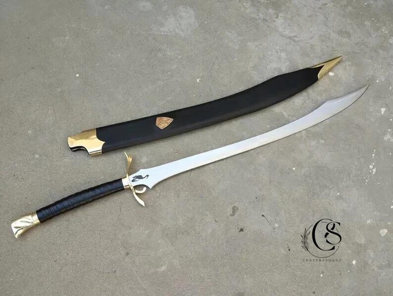以下が含まれることがあります： 銀色の刃と黒いグリップで包まれた黒い柄の湾曲した剣。 ヒルトとポメルは金色です。 黒い鞘には金色のアクセントと金色のエンブレムが付いています。 剣は灰色の表面に置かれています。