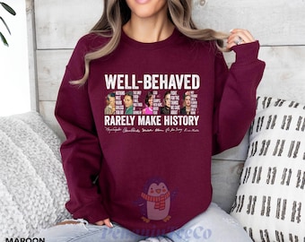May include: Maroon sweatshirt with a white graphic print that says "Well-Behaved Rarely Make History". The graphic features a group of people with quotes about leadership, hope, and fighting for what is right.