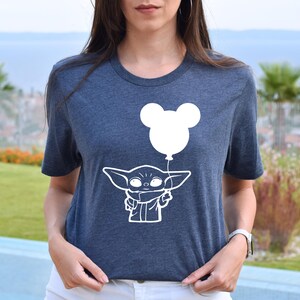 A woman wearing a blue t-shirt with a white graphic of a young child holding a balloon.