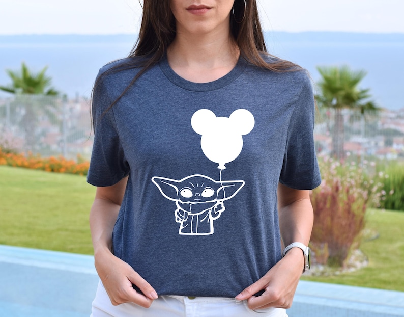 A woman wearing a blue t-shirt with a white graphic of a young child holding a balloon.