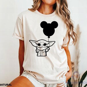 A woman wearing a white t-shirt with a graphic of a young child holding a balloon.