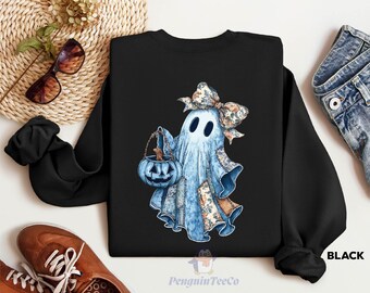 May include: Black crewneck sweatshirt featuring a watercolor ghost with a floral bow and a blue pumpkin bucket. The ghost has a patchwork design and is holding a jack-o'-lantern. The text "PenguinTeeCo" is at the bottom.