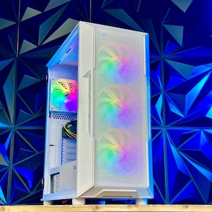 May include: A white computer case with three front-facing fans and a side fan, all displaying a rainbow of colors. The case is open, revealing internal components. The background is a textured blue wall.