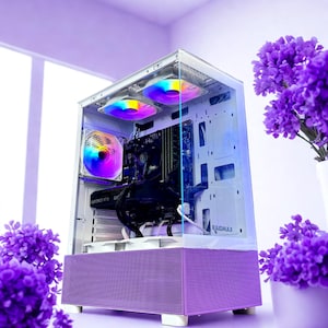 May include: A white computer case with a purple front panel and clear side panel, showcasing internal components. The case features multiple fans with rainbow LED lighting. The image is styled with purple flowers and a soft, diffused lighting.
