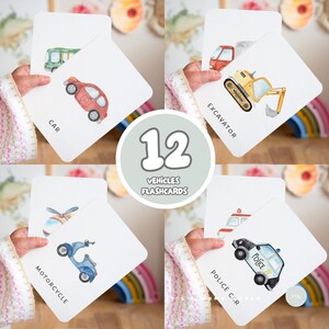 Op de afbeelding: Een set van 12 voertuig flashcards. Elke kaart bevat een aquarel illustratie van een voertuig, waaronder een auto, graafmachine, motorfiets en politieauto. De kaarten worden in de handen van een persoon gehouden, met de namen van de voertuigen eronder.