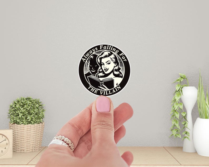 Op de afbeelding: Zwart-witte sticker met een vrouw die een boek leest. De tekst luidt "Always Falling For The Villain".