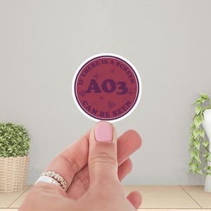 May include: A round sticker with a burgundy background and white text that reads "If there is a screen A03 can be seen". The sticker has a white border and a few small white stars and hearts.