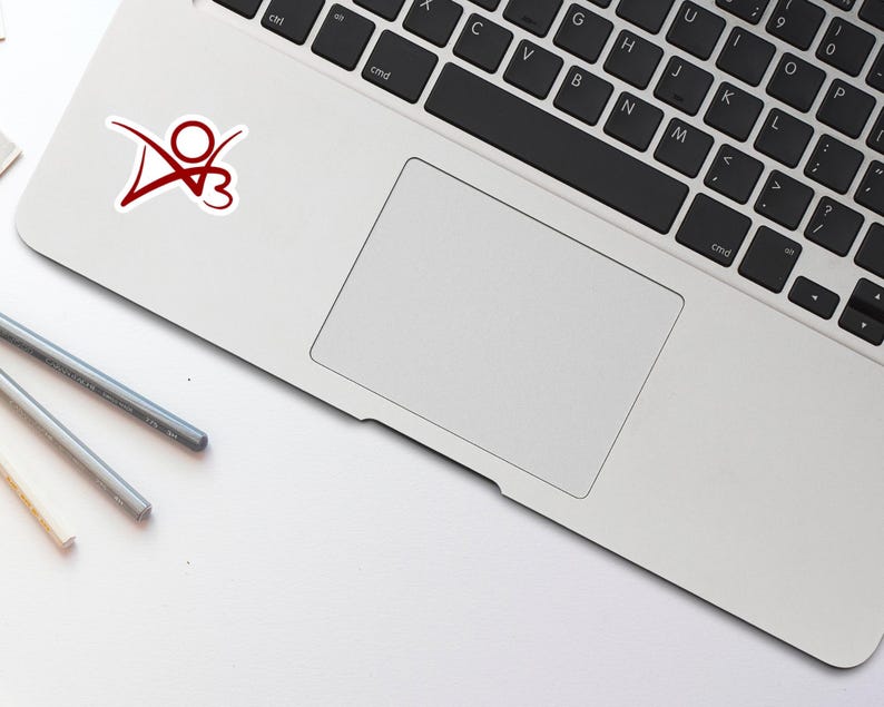 May include: A silver laptop computer with a red sticker of a stylized person with a heart on a white background. The laptop is closed and the keyboard is visible.