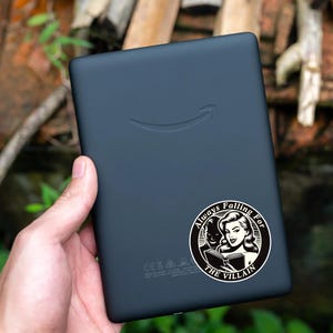 Op de afbeelding: Zwart-witte sticker met een vrouw die een boek leest. De sticker zegt "Always Falling For The Villain".