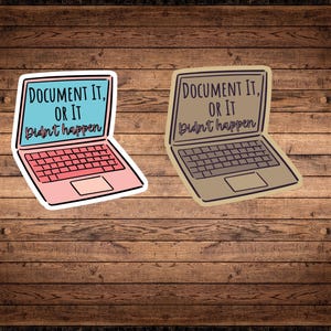 Peut inclure: Deux autocollants pour ordinateur portable avec le texte "DOCUMENT IT, OR IT didn't happen". L'un est rose avec un écran bleu, l'autre est beige avec un écran gris. Les autocollants sont sur un fond en bois.
