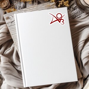 May include: A white blank journal with a red logo sticker on the front cover. The logo is a stylized letter "D" with a circle and the number "3" inside the circle.