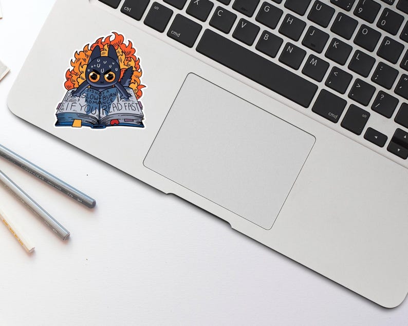 May include: A black and blue sticker of a cartoon dragon reading a book with the text "Glowburn Romance. If you read fast." The dragon is surrounded by flames.