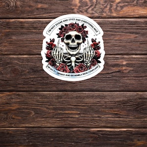 May include: A white sticker featuring a black skeleton wearing a red flower crown. The skeleton is giving the middle finger with both hands. The text on the sticker reads "I'm not sugar and spice and everything nice. I'm salty, defiant and extremely non compliant."