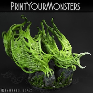 May include: A green, monstrous dragon sculpture with a detailed, textured design. The dragon has large, wing-like structures and is perched on a rocky base with skulls and vegetation. The text "PRINTYOURMONSTERS" is at the top.