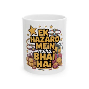 Puede incluir: Taza de cerámica blanca con el texto "EK HAZARO MEIN mera BHAI HAI" en amarillo y negro. El diseño incluye ilustraciones de regalos, pulseras y estrellas. Un tema festivo y de celebración.