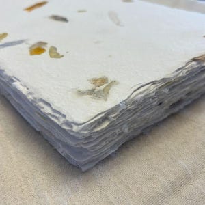 Op de afbeelding: Een set van drie keramische mokken met een gespikkelde, matte afwerking. De mokken zijn in crème, lichtgrijs en donkergrijs. Elke mok heeft een eenvoudig, minimalistisch ontwerp en een afgeronde handgreep.