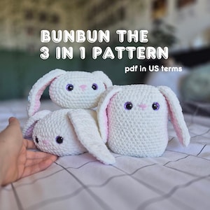 Könnte beinhalten: Drei weiße Häkeltier-Hasen mit rosa Ohren und lila Augen werden gezeigt. Der Text "BUNBUN THE 3 IN 1 PATTERN" befindet sich oben. Der Satz "pdf in US terms" ist ebenfalls sichtbar.