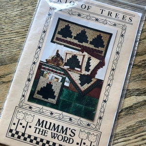 May include: A craft pattern for a trio of Christmas tree quilts. The pattern is titled "Trio of Trees" and is from "Mumm's The Word". The pattern shows a quilt with three trees, a pillow with a tree, and a small quilted bag with a tree.