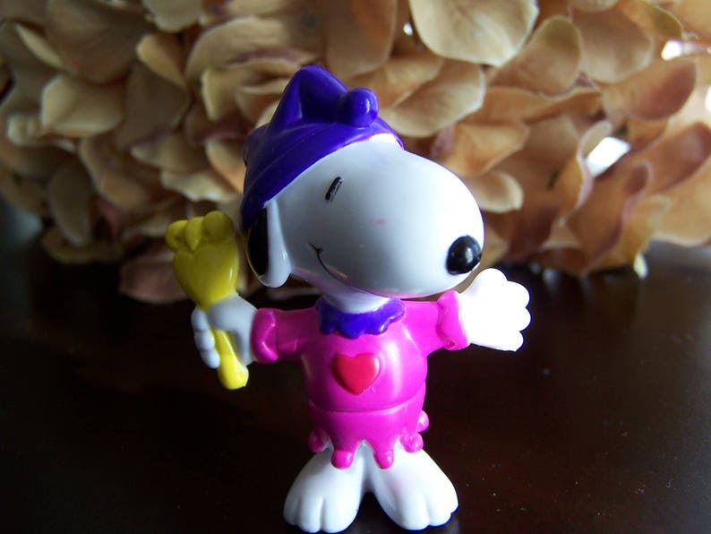 May include: A white and purple cartoon character wearing a pink dress with a heart on the front and holding a yellow wand.