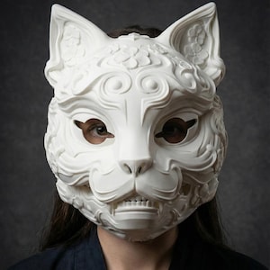 Könnte beinhalten: Eine weiße Katzenmaske mit aufwendigen floralen und Wirbeldetails. Die Maske hat große, spitze Ohren und Augenöffnungen. Die Maske wird von einer Person mit dunklem Haar und einem dunkelblauen Oberteil getragen. Das Design der Maske umfasst eine detaillierte Nase, Mund und Zähne.