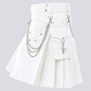 May include: A white kilt with pleats, a pocket, and silver-tone chain detailing. The kilt has a belt with silver hardware and decorative rivets. A silver chain hangs from the belt to the pocket.