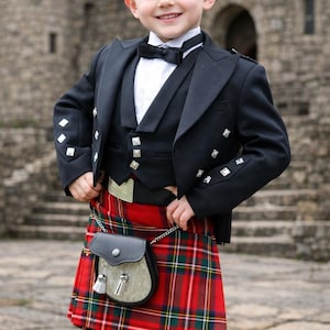 Könnte beinhalten: Ein junger Junge in traditioneller schottischer Tracht. Er trägt eine schwarze Jacke, Weste und Fliege über einem weißen Hemd. Der Kilt ist rot mit einem grün-schwarzen Karomuster. Eine kleine schwarze Leder-Sporran hängt daran.