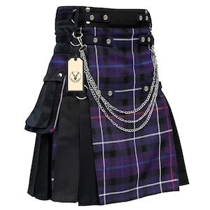 Könnte beinhalten: Ein Kilt mit lila und schwarzem Karomuster und silbernen Kettenakzenten. Der Kilt hat einen schwarzen Bund mit silbernen Nieten und eine schwarze Seitenverkleidung mit einer Tasche. Ein Anhänger mit einem Hirschlogo hängt an der Kette.