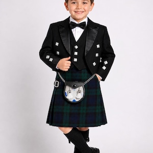 May include: A young person wearing a formal Scottish outfit. The ensemble includes a black jacket with white accents, a vest, a bow tie, and a green and blue plaid kilt. A small leather sporran hangs from the waist, and black knee socks and shoes complete the look.