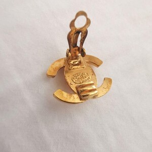 Puede incluir: Pendientes de clip Chanel de color dorado con el logotipo de Chanel en la parte posterior. Los pendientes est&aacute;n hechos de metal y tienen un dise&ntilde;o cl&aacute;sico.