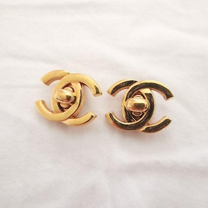 Puede incluir: Un par de pendientes Chanel de tono dorado con el ic&oacute;nico logotipo CC entrelazado. Los pendientes son simples y elegantes, y ser&iacute;an un gran regalo para cualquier fan de Chanel.