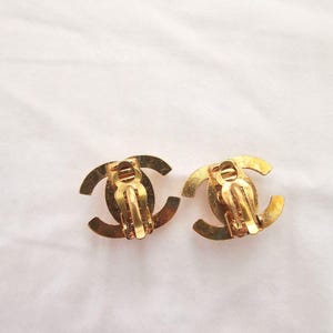 Puede incluir: Un par de pendientes de clip en tono dorado con el ic&oacute;nico logotipo de doble 'C' de Chanel.