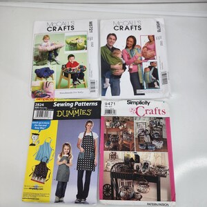 May include: Four sewing pattern packets. Two McCall's Crafts patterns feature babies and baby items. One Simplicity Sewing Patterns for Dummies packet shows aprons. A Simplicity Crafts pattern packet shows various craft projects.