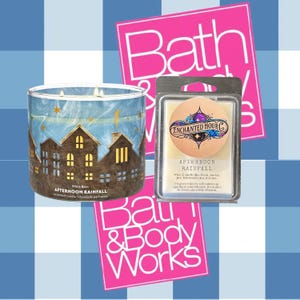 May include: A blue and brown candle with a winter village design and the text "White Barn Afternoon Rainfall Scented Candle" on the front. The candle is next to a wax melt with the text "Enchanted Hour Co. Afternoon Rainfall" on the front. Both products are from Bath & Body Works.