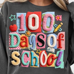 May include: Dark gray sweatshirt with a colorful graphic celebrating 100 Days of School. The design features the number "100" in white and pink, along with other school-themed elements like an apple, pencil, and open book.