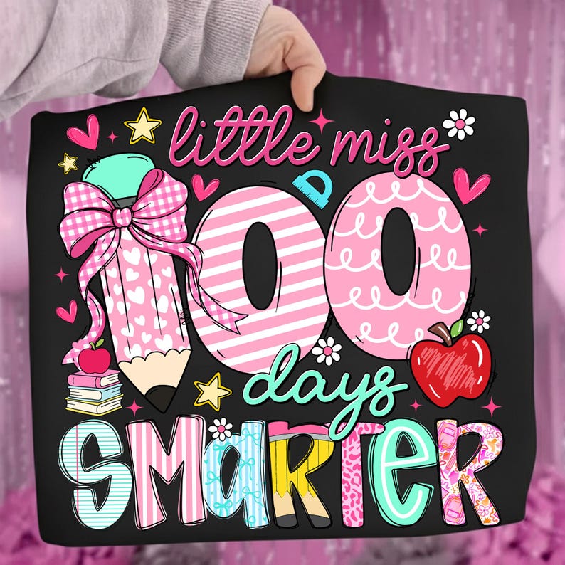 Puede incluir: Bolso tote negro con el texto "little miss 100 days smarter". El dise&ntilde;o incluye un l&aacute;piz rosa con un lazo, corazones rosas, estrellas y una manzana roja. Los n&uacute;meros "100" son de rayas rosas y blancas.