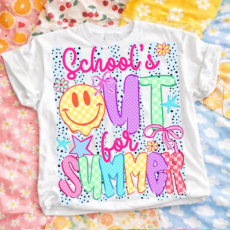 Puede incluir: Camiseta blanca con un gr&aacute;fico colorido que dice "School's Out for Summer". El dise&ntilde;o incluye una carita sonriente, flores, estrellas y las palabras en varios colores y patrones. La camiseta est&aacute; doblada.