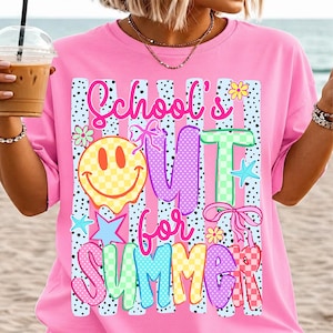 Puede incluir: Camiseta rosa con la frase "School's Out for Summer" en letras coloridas y divertidas. El dise&ntilde;o incluye una carita sonriente a cuadros, estrellas, flores y lazos, creando un ambiente veraniego y divertido. La camiseta tiene un corte holgado.