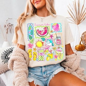 Puede incluir: Camiseta color crema con un gr&aacute;fico colorido de tem&aacute;tica veraniega. El dise&ntilde;o incluye una rodaja de sand&iacute;a, sol, c&aacute;mara, pulpo, cono de helado y el texto "Summer Vibes". La camiseta se combina con pantalones cortos vaqueros.