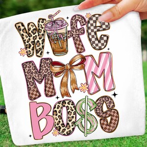 May include: White towel with the words "Wife Mom Boss" in various fonts and patterns. The word "Wife" has a leopard print design, and "Mom" has a bow. A coffee drink with a straw is also featured.