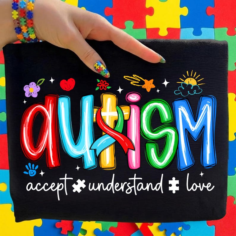 May include: Black t-shirt with the word "AUTISM" in colorful letters, accented with stars, hearts, and a sun graphic. Below, the words "accept, understand, love" are written in white.