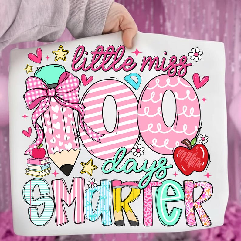 Puede incluir: Bolso tote blanco con un dise&ntilde;o colorido que celebra los 100 d&iacute;as de escuela. Presenta un gran l&aacute;piz rosa, las palabras "little miss 100 days smarter", corazones, estrellas y una manzana.