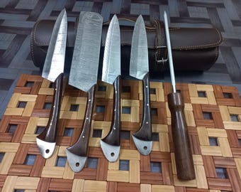 以下が含まれることがあります： 木製のハンドルと収納用の革巻きが付いた5本のキッチンナイフのセット。ナイフはダマスカス鋼の刃模様です。