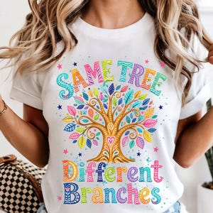 May include: White t-shirt featuring a vibrant tree design. The tree has a brown trunk and multi-coloured leaves. The text "Same Tree Different Branches" is displayed above and below the tree in colourful letters.