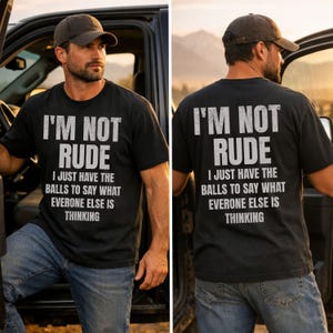 May include: Black t-shirt with the text "I'M NOT RUDE I JUST HAVE THE BALLS TO SAY WHAT EVERONE ELSE IS THINKING" in white block letters. The shirt is worn with blue jeans and a brown cap.