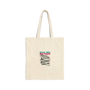 May include: Cream-coloured tote bag featuring the text "Error 404: Not Found" in teal and red, with a graphic of computer window icons. The bag has two long handles.