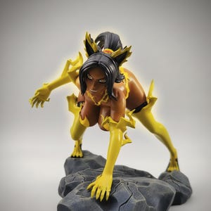 Peut inclure: Figurine d'une femme aux cheveux noirs et aux accents jaunes, dans une pose dynamique. La figurine est sur une base rocheuse, avec des extensions jaunes sur les bras et les jambes. La peau de la femme est brune, et la figurine est détaillée.