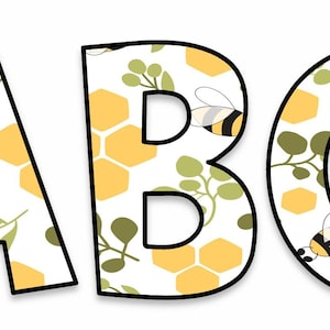 Peut inclure: Les lettres A, B et C sont affichées, chacune avec un contour noir. Les lettres sont remplies d'un motif de nids d'abeilles jaunes, de feuilles vertes et d'abeilles. Le fond est blanc.