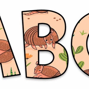 May include: The letters A, B, and C are displayed, each with a black outline. The letters are filled with a tan pattern featuring armadillos, flowers, and cacti. The armadillos are brown with tan spots.