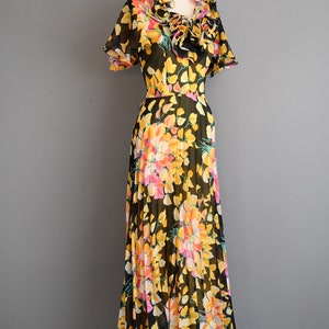 May include: A black maxi dress with a floral print featuring yellow, pink, and orange flowers. The dress has a ruffled neckline and short sleeves.